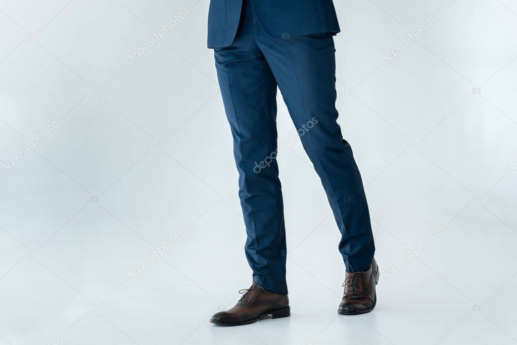 cropped image of businessman in blue suit and brown shoes standing isolated on white