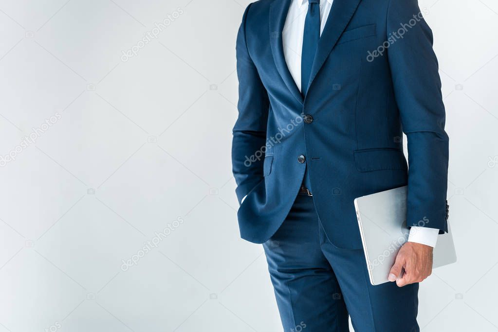 midsection of businessman standing with laptop isolated on white
