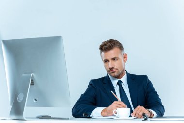 yakışıklı işadamı bilgisayar üzerinde beyaz izole masada bakarak