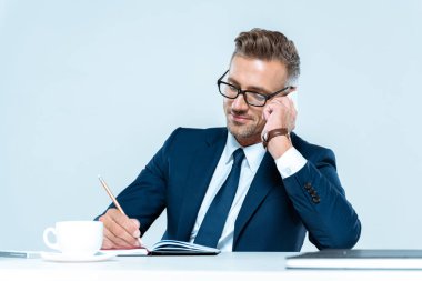 bir şey yazma ve yanında beyaz izole smartphone konuşurken yakışıklı neşeli işadamı