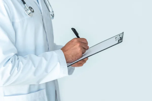 裁剪的图像医生与听诊器在肩膀上写的东西在剪贴板孤立在白色 — 图库照片