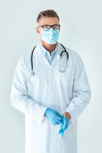 英俊的医生在医疗口罩戴着医疗手套 看着相机孤立的白色 — 免费的图库照片