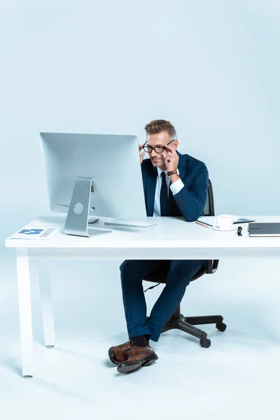 Stilig Affärsman Bär Glasögon Och Tittar Dator Vid Bord Isolerad — Gratis stockfoto