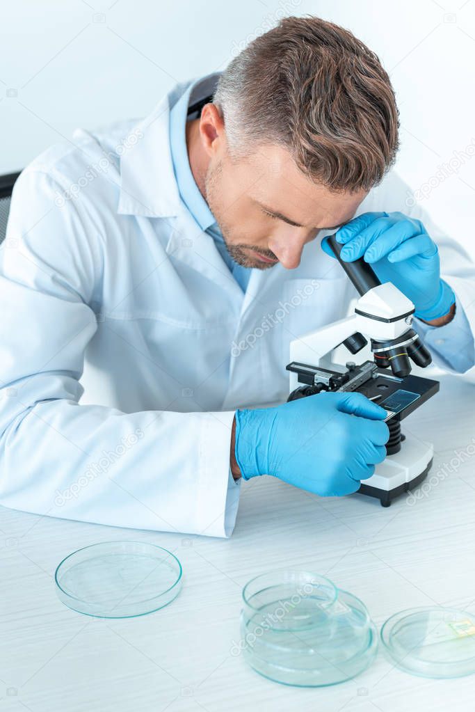 handsome scientist making test with microscope isolated on white