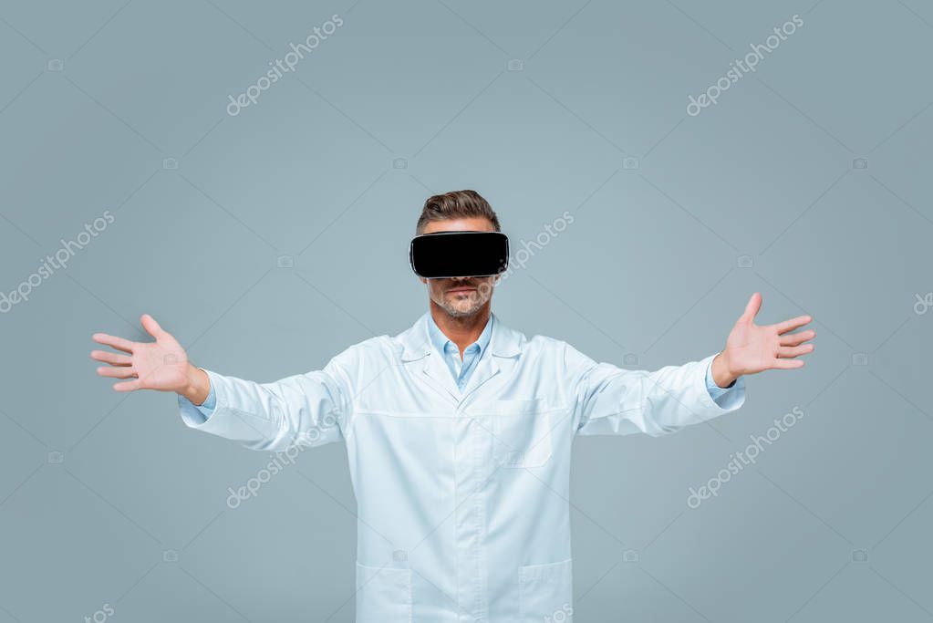 Scientist in virtual reality headset holding something in open arms isolated on grey, artificial intelligence concept