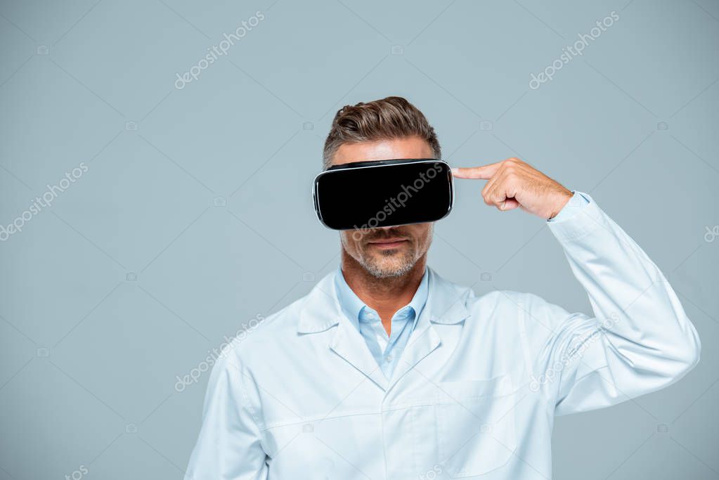 Scientist  in virtual reality headset pointing on his head isolated on grey, artificial intelligence concept