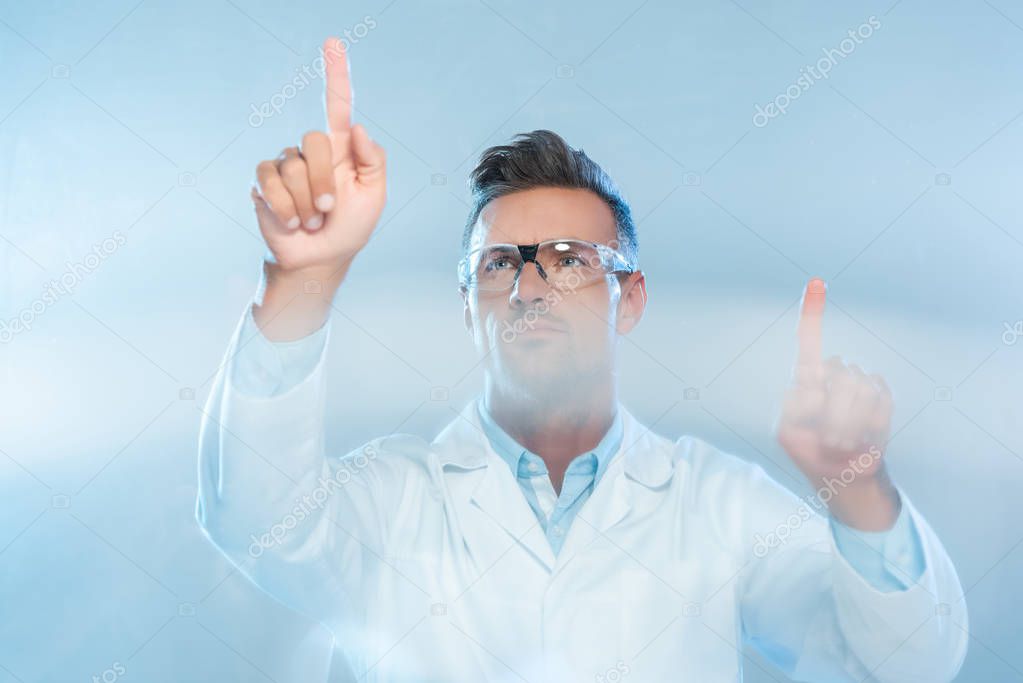 Handsome scientist in protective glasses and white coat touching something isolated on white, artificial intelligence concept