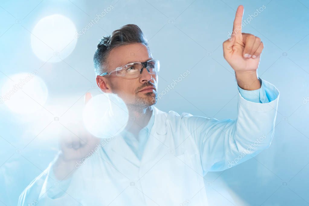 Handsome technologist in protective glasses and white coat touching something isolated on white, artificial intelligence concept