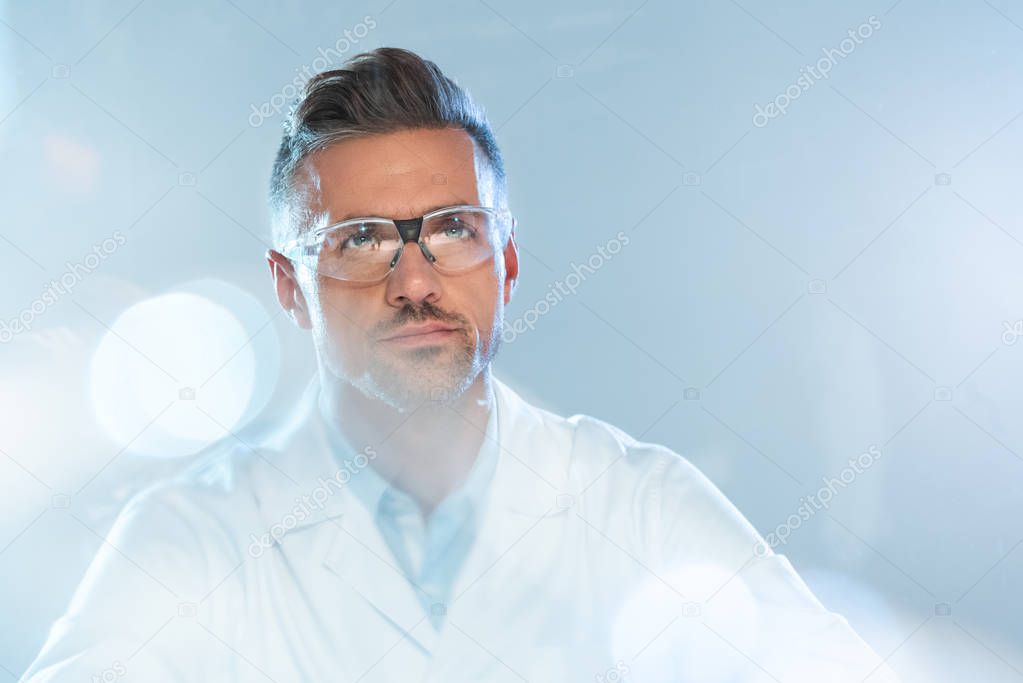 Portrait of handsome scientist in protective glasses looking up isolated on white, artificial intelligence concept