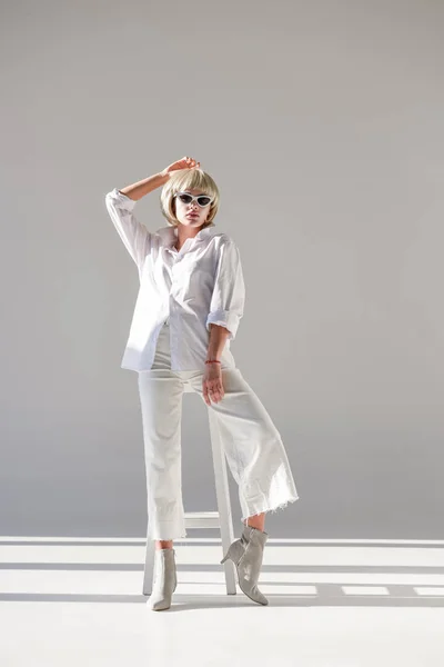 Привлекательная Блондинка Солнечных Очках Модном Белом Наряде Позирует Возле Стула — Бесплатное стоковое фото
