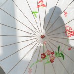 Silhouet van de vrouw permanent met witte Japanse paraplu in de buurt van venster