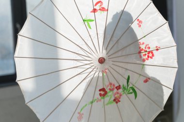 pencere yakınındaki beyaz Japon şemsiye ile duran kadın silüeti