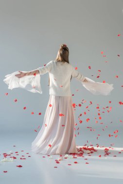 arkadan görünüşü çekici kadın etrafında altında düşen kırmızı gül yaprakları üzerinde beyaz iplik moda kış kıyafeti