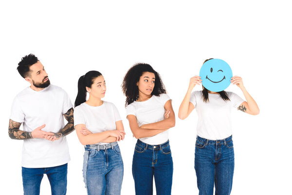 multicultural friends looking at girl with winking sign isolated on white