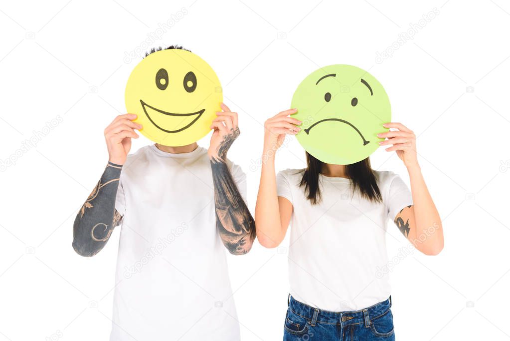 young couple holding colourful cards with face expressions isolated on white