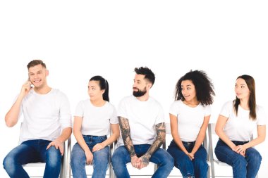 smartphone üzerinde beyaz izole sandalyelere oturan genç insanlar çok ırklı grup sırasında konuşan genç gülümseyen adam