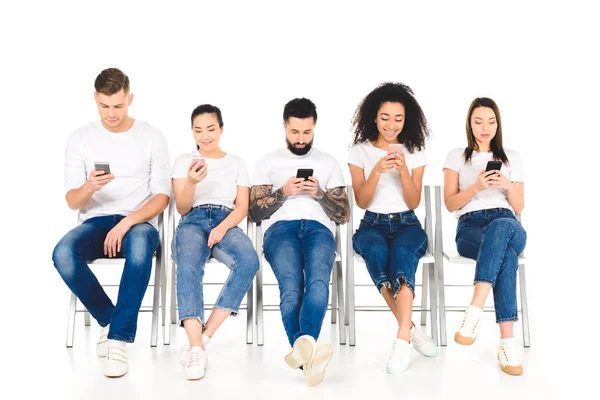 Grupo Multicultural Jovens Sentados Cadeiras Com Smartphones Isolados Branco — Fotografia de Stock