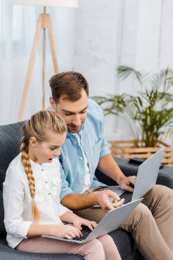 kanepede oturan ve laptop sürpriz kızın parmak ile işaret eden yakışıklı babası