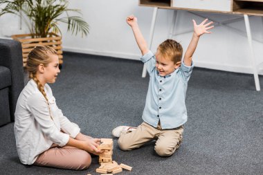 mutlu çocuk yetiştirme ile eller ve katta oturan ve oynayan sevimli kız evinde ahşap kule oyun bloklar