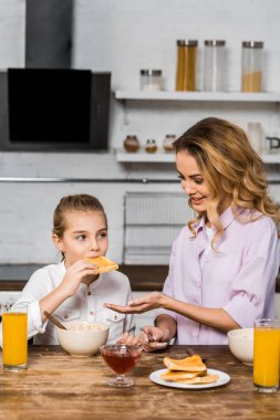 gülümseyen anne şirin kızı tost reçelli yeme bakarak