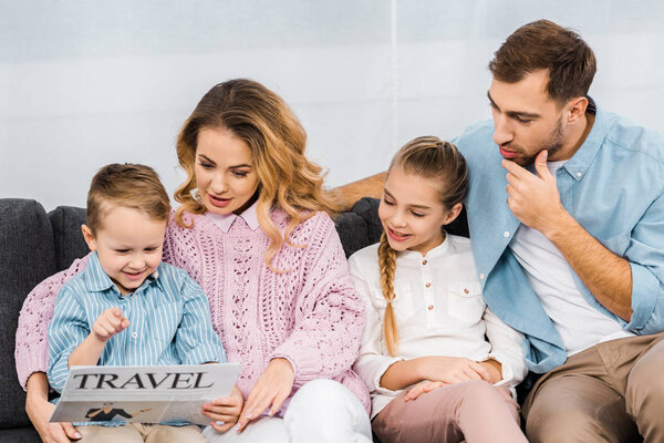happy family sitting on sofa and reading travel newspaper in living room