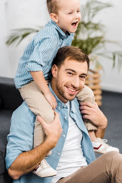 Smiling Boy Sitting Shoulders Father Looking Camera Living Room — Stock Photo, Image