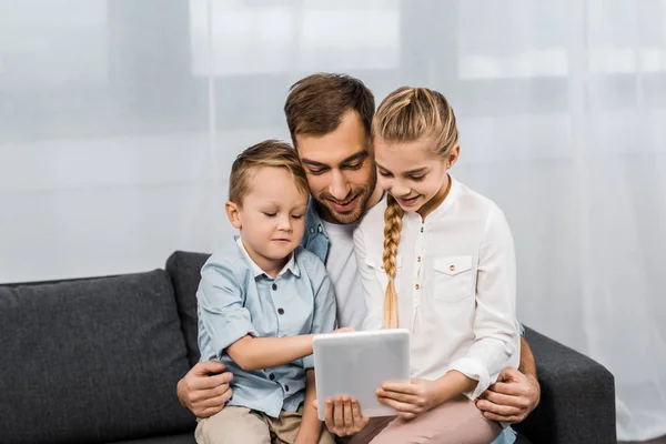 Smiling Father Siting Sofa Embracing Boy Girl Holding Digital Tablet — Stock Photo, Image