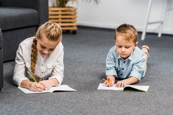 Linda Chica Niño Tumbado Suelo Escritura Cuadernos Sala Estar — Foto de Stock