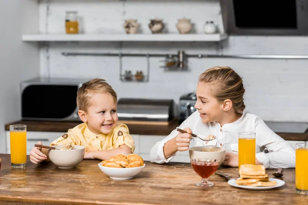 Lächelnde Geschwister Essen Brei Tisch Und Schauen Einander — kostenloses Stockfoto