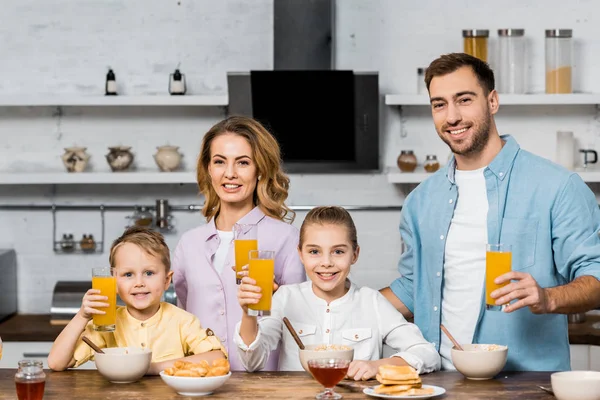 笑顔の両親と子供とオレンジ ジュースのガラスを保持しています — ストック写真