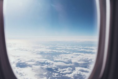 Uçak penceresinden mavi bulutlu gökyüzü görünümü