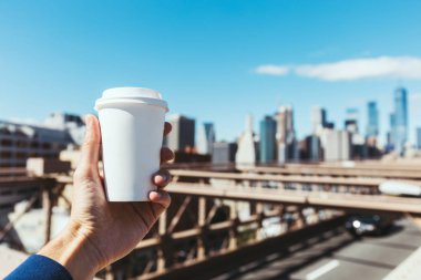Tek kullanımlık bardak kahve ile bulanık new York'un arka planda tutan adamın kısmi görünümü