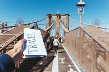 bir arka plan üzerinde bulanık new york city Köprüsü manzaralı seyahat gazete tutan adam kısmi görünümü