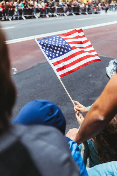 close up view of american flag in childs hands during parade on street in new york, usa