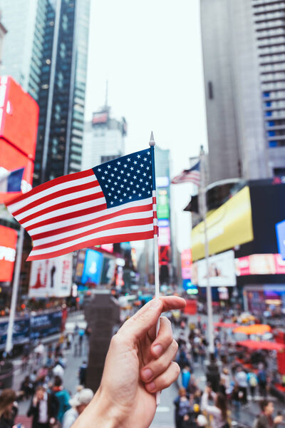 partial view of man holding american flag on new york city street