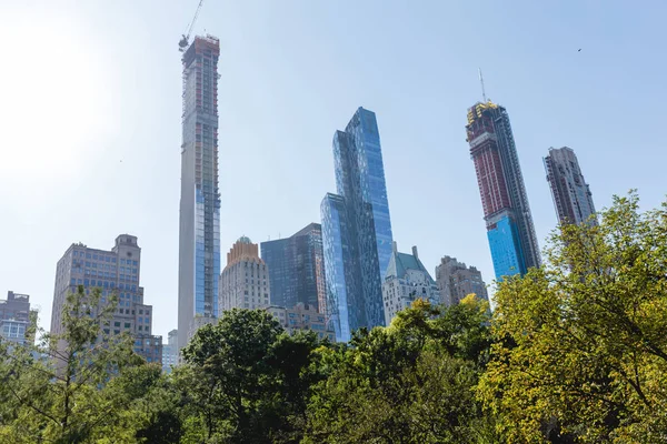 urban scene with trees in city park and skyscrapers in new york, usa