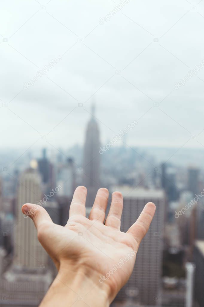 partial view of male hand and blurry new york city view on background