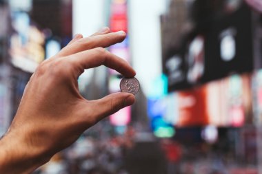 NEW YORK, USA - OCTOBER 8, 2018: partial view of man holding cent in hand with blurred new york city street on background clipart
