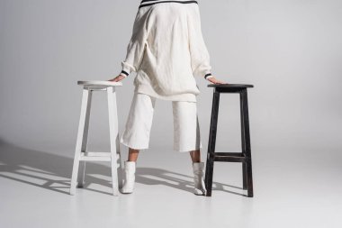 kız moda kazak ve pantolon beyaz üzerine siyah ve beyaz sandalye arasında ayakta kırpılmış görüntü
