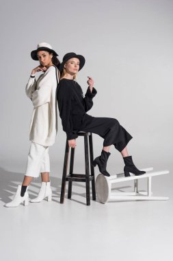 siyah ve beyaz giysili sandalye beyaz ile poz çekici çok ırklı kadınlar