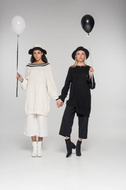 güzel çok kültürlü kaç siyah beyaz elbise eller ve beyaz üzerine iki balon tutuyor içinde