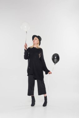 beautiful caucasian blonde woman in black clothes and hat holding balloons on white clipart