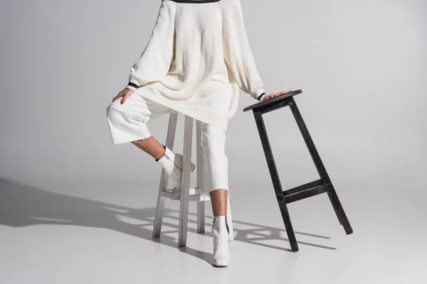 Przycięte Zdjęcie Dziewczyny Stylowy Biały Sweter Spodnie Siedzi Krześle Biały — Zdjęcie stockowe