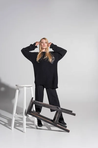 Beautiful Caucasian Blonde Woman Black Sweater Standing Chairs White — Free Stock Photo