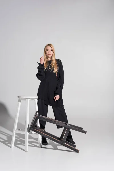 Beautiful Caucasian Blonde Woman Black Clothes Standing Chairs Looking Camera — Free Stock Photo