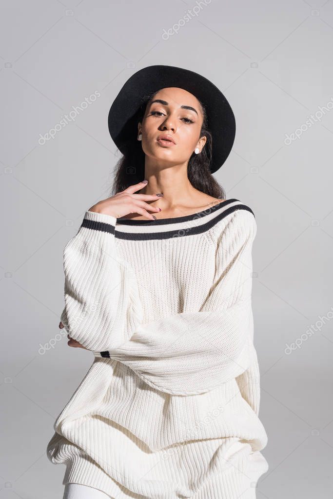 portrait of attractive african american girl in stylish white clothes and hat looking at camera on white