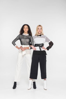 eller üzerinde beyaz izole kamera bakarak akimbo ile siyah beyaz giysili güzel çok kültürlü kadınlar