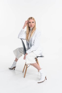 güzel kadın sandalyede oturan ve üzerinde beyaz izole kamera bakıyor beyaz giyimleri