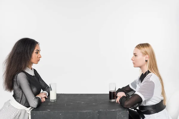 ミルクとホワイトに分離されたソーダのテーブルに座って黒と白の服で美しい多文化女性の側面図 — ストック写真