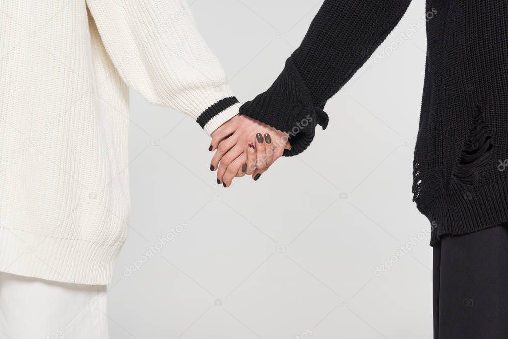 cropped image of multicultural lesbian couple in black and white clothes holding hands isolated on white